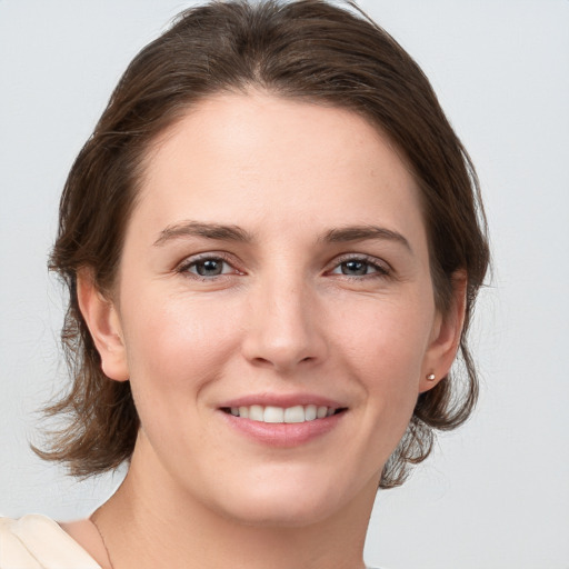 Joyful white young-adult female with medium  brown hair and grey eyes