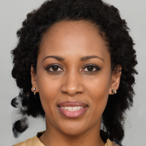 Joyful black young-adult female with long  black hair and brown eyes