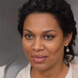 Joyful black adult female with long  brown hair and brown eyes