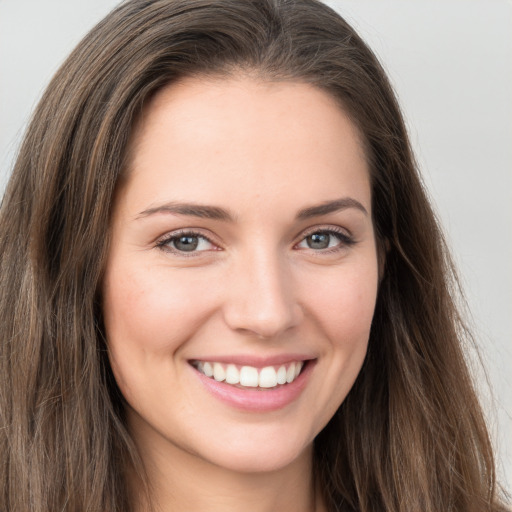 Joyful white young-adult female with long  brown hair and grey eyes