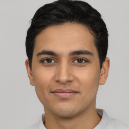 Joyful latino young-adult male with short  brown hair and brown eyes