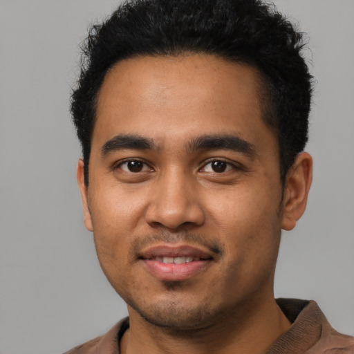 Joyful latino young-adult male with short  black hair and brown eyes