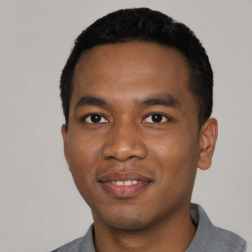 Joyful black young-adult male with short  black hair and brown eyes