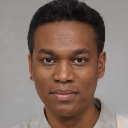 Joyful black young-adult male with short  black hair and brown eyes