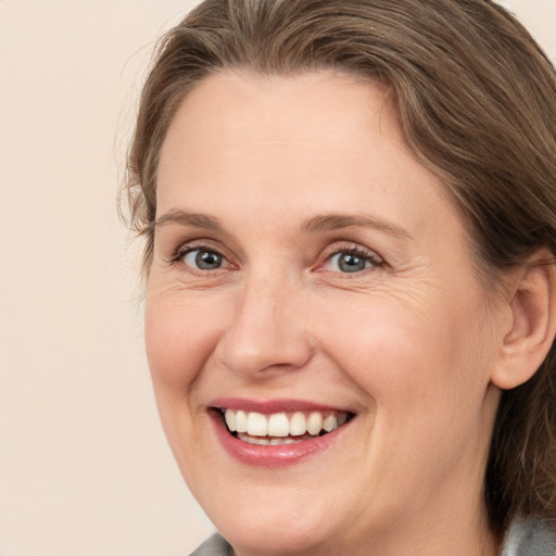 Joyful white adult female with medium  brown hair and grey eyes