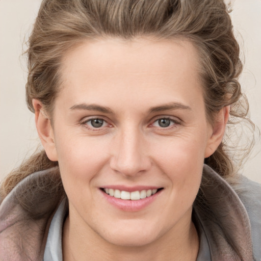 Joyful white young-adult female with medium  brown hair and grey eyes