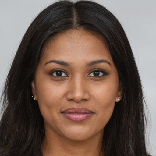 Joyful black young-adult female with long  brown hair and brown eyes