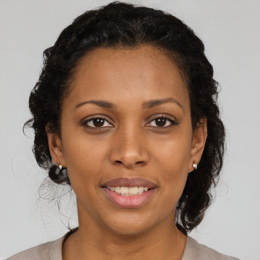 Joyful black young-adult female with long  brown hair and brown eyes