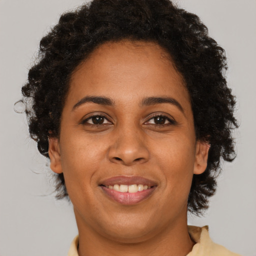 Joyful black young-adult female with short  brown hair and brown eyes