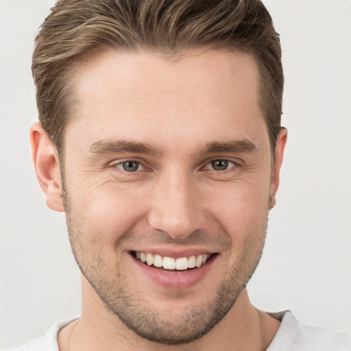 Joyful white young-adult male with short  brown hair and grey eyes