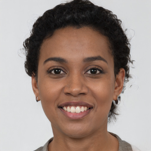 Joyful black young-adult female with short  black hair and brown eyes