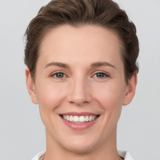 Joyful white young-adult female with short  brown hair and grey eyes