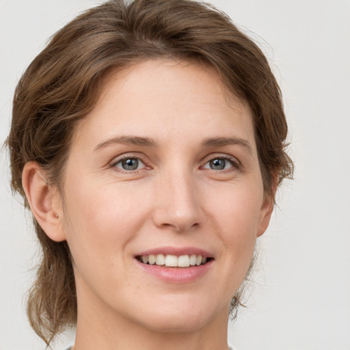 Joyful white young-adult female with medium  brown hair and grey eyes