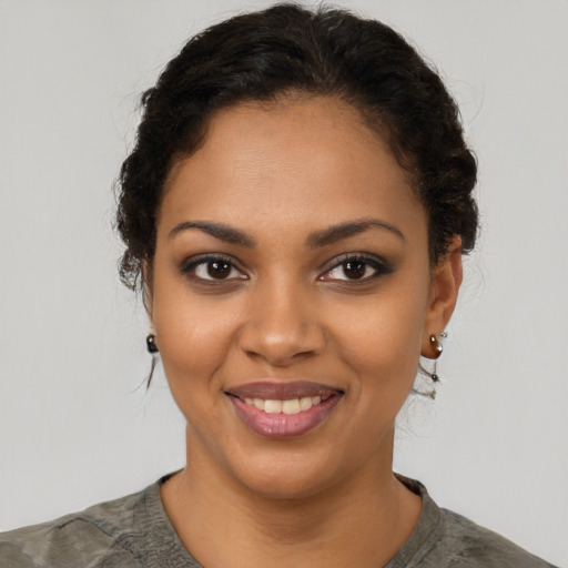 Joyful black young-adult female with short  black hair and brown eyes