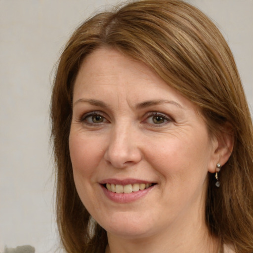 Joyful white adult female with medium  brown hair and green eyes