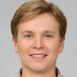 Joyful white young-adult male with short  brown hair and grey eyes