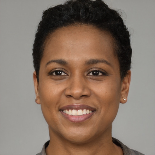 Joyful black young-adult female with short  black hair and brown eyes