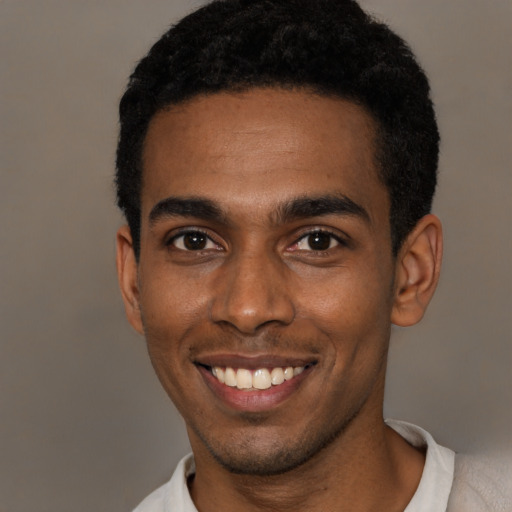 Joyful black young-adult male with short  black hair and brown eyes