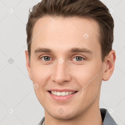 Joyful white young-adult male with short  brown hair and grey eyes