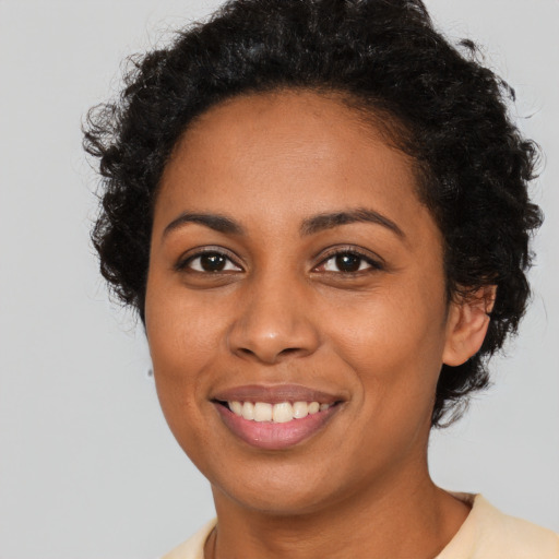Joyful black young-adult female with short  black hair and brown eyes
