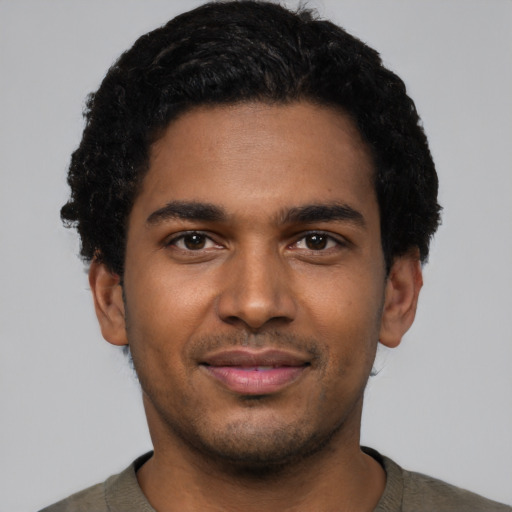 Joyful black young-adult male with short  black hair and brown eyes