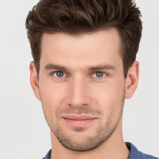 Joyful white young-adult male with short  brown hair and grey eyes