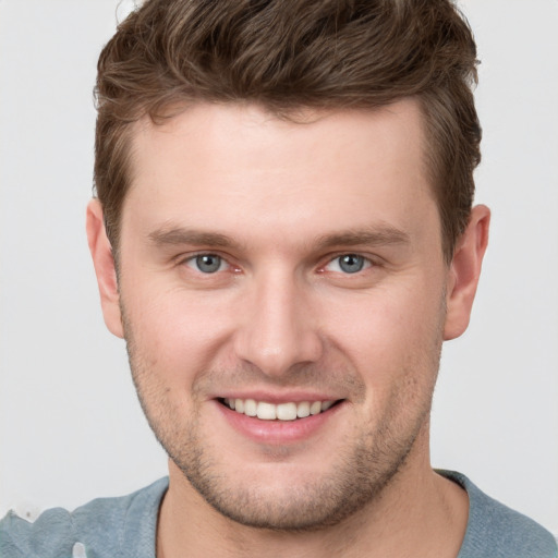 Joyful white young-adult male with short  brown hair and grey eyes