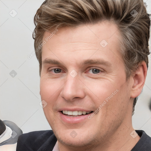 Joyful white young-adult male with short  brown hair and grey eyes