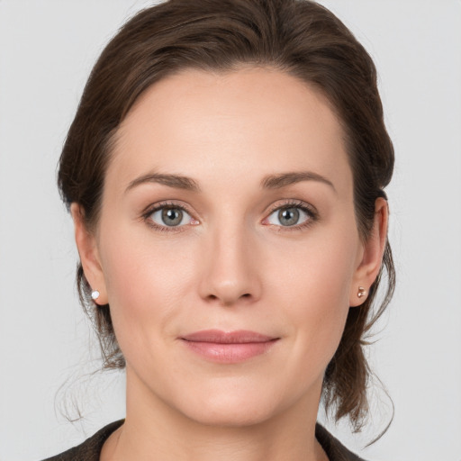 Joyful white young-adult female with medium  brown hair and grey eyes