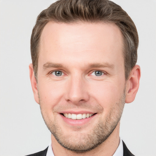 Joyful white young-adult male with short  brown hair and grey eyes