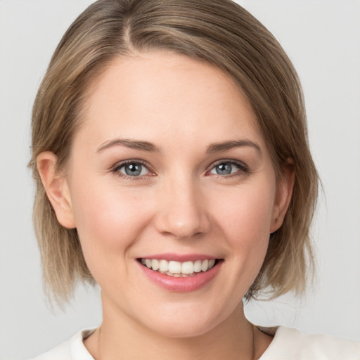 Joyful white young-adult female with medium  brown hair and grey eyes