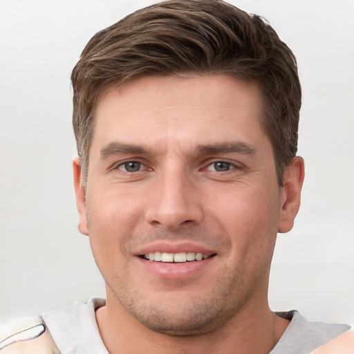 Joyful white young-adult male with short  brown hair and grey eyes