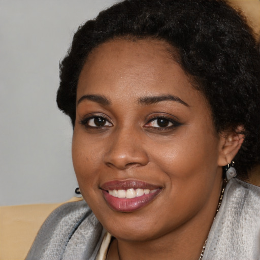 Joyful black young-adult female with short  black hair and brown eyes