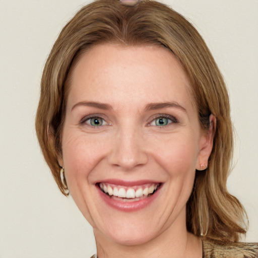 Joyful white adult female with medium  brown hair and green eyes