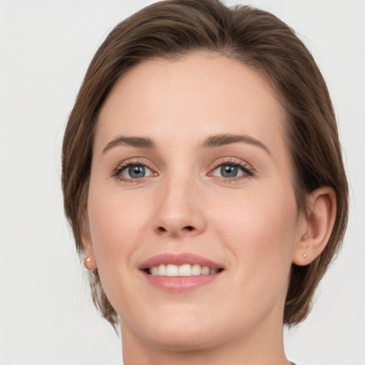 Joyful white young-adult female with medium  brown hair and grey eyes