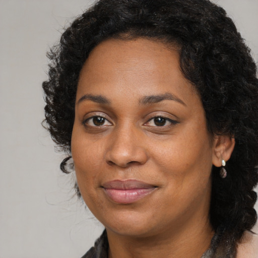 Joyful black young-adult female with long  brown hair and brown eyes