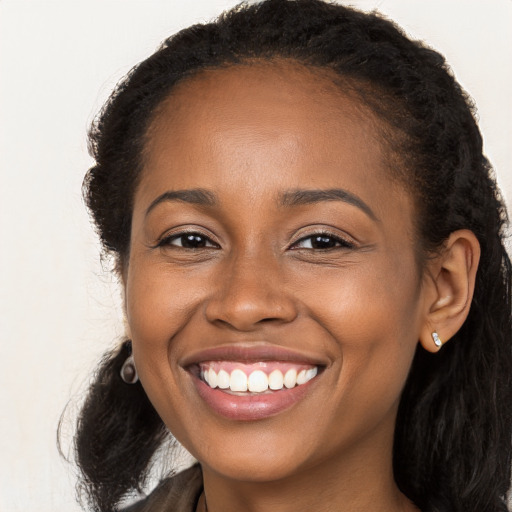 Joyful black young-adult female with long  brown hair and brown eyes