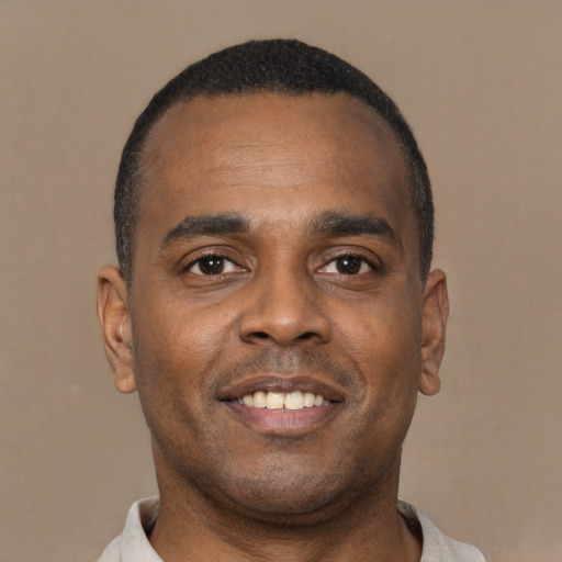 Joyful black young-adult male with short  brown hair and brown eyes