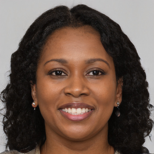 Joyful black young-adult female with long  brown hair and brown eyes