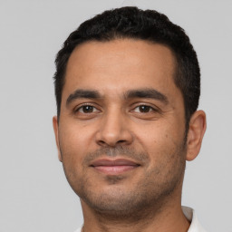 Joyful latino young-adult male with short  black hair and brown eyes