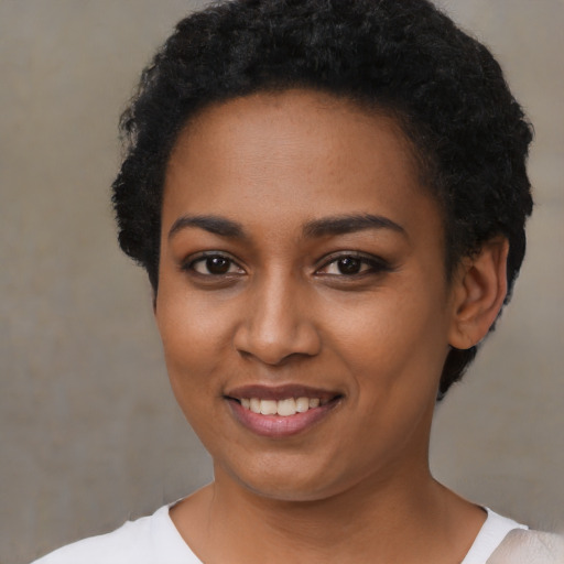 Joyful black young-adult female with short  black hair and brown eyes