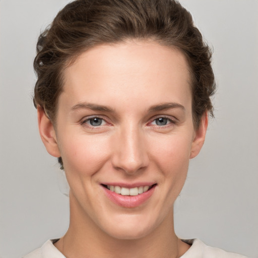 Joyful white young-adult female with short  brown hair and grey eyes