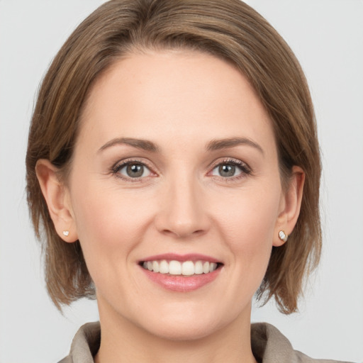 Joyful white young-adult female with medium  brown hair and grey eyes