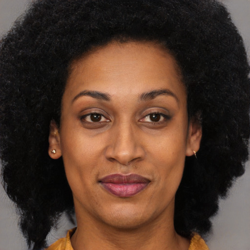 Joyful black adult female with long  brown hair and brown eyes