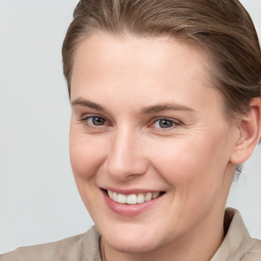 Joyful white young-adult female with medium  brown hair and grey eyes