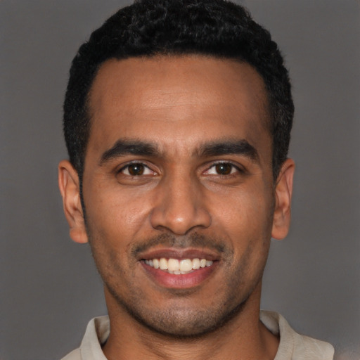 Joyful black young-adult male with short  black hair and brown eyes