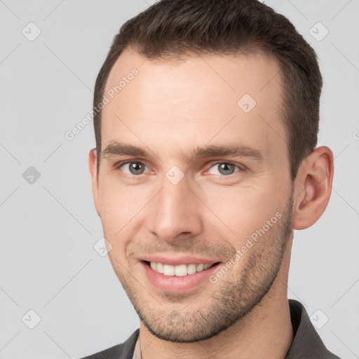 Joyful white young-adult male with short  brown hair and grey eyes