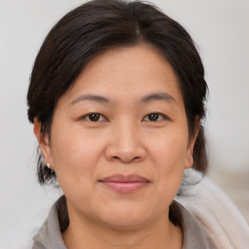 Joyful asian adult female with medium  brown hair and brown eyes