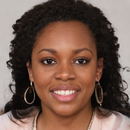 Joyful black young-adult female with long  brown hair and brown eyes