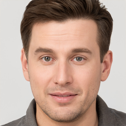 Joyful white young-adult male with short  brown hair and grey eyes